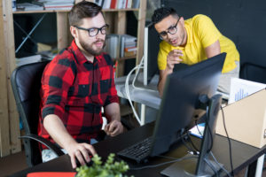 Two men using a computer to work