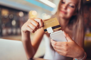 Woman in cafe making mobile payment with credit card