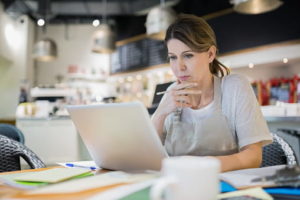 Serious business owner working at laptop in cafe