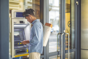 Young man is withdrawing money from an ATM