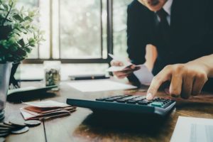 man-using-calculator-on-desk-holding-receipts