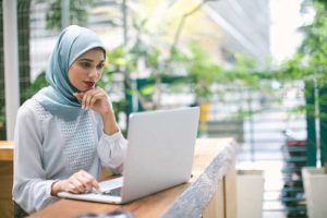 woman wearing a headscarf working on a laptop