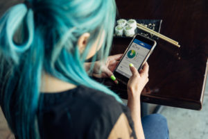 Feature image of a woman with dyed-blue hair checking a budgeting app on her smartphone