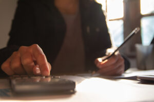 Featured image close-up of a woman typing on a calculator at a desk