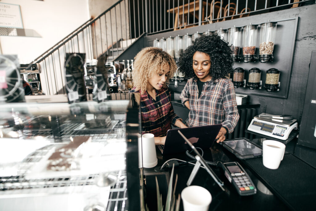 Two young women in a restaurant looking at a computer