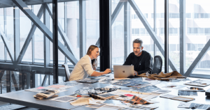 women and man working on laptop at table cover in fabric samples