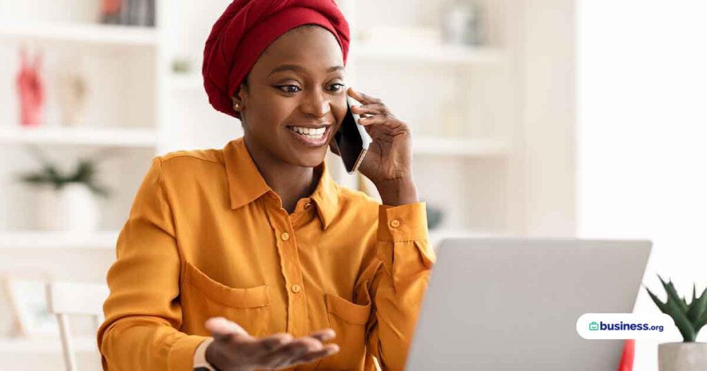 woman-talking-on-phone-while-using-laptop