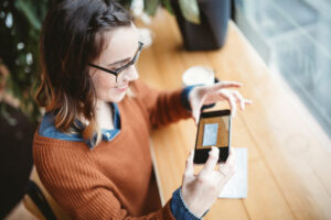 Woman using mobile deposit for a check in a cafe