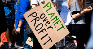 A cardboard sign reading "Planet over profit."