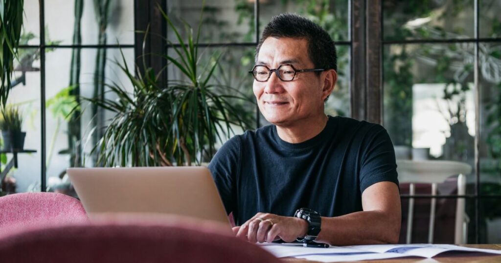 Smiling man working on laptop and finding ways to be productive productive