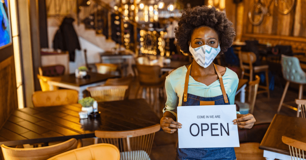 A worker holds an open sign