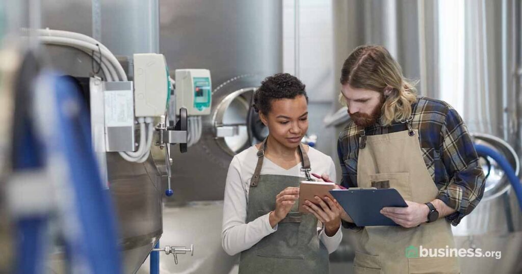 Two employees work at a brewery.