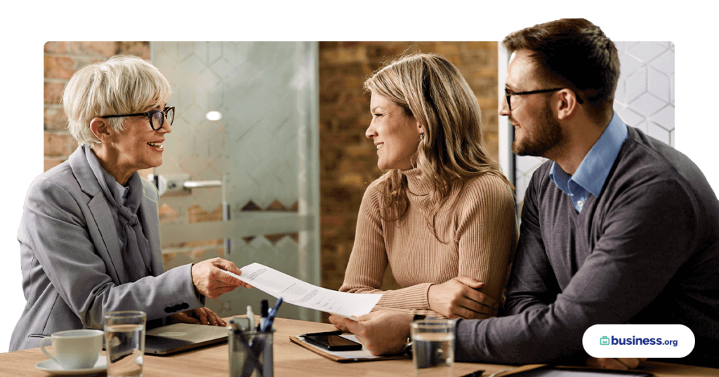 happy couple working with woman wearing glasses going over paperwork