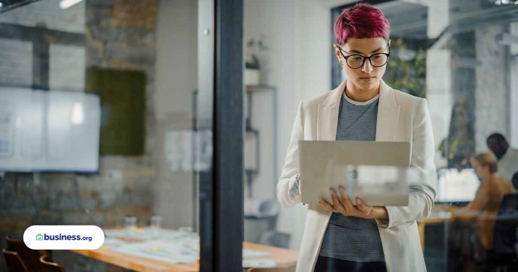 person with pink hair using laptop in office