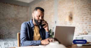 male in home office using computer while on a phone call