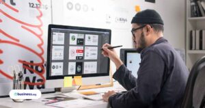 person sitting at computer wearing hat and designing website