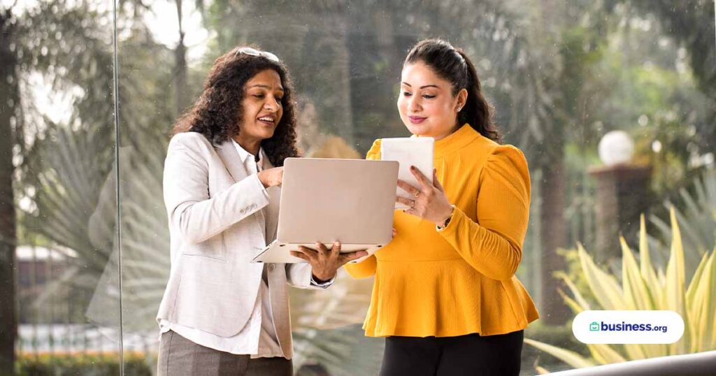 two business woman using computer in front of window