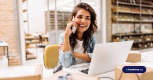 woman talking on phone while using computer in warehouse