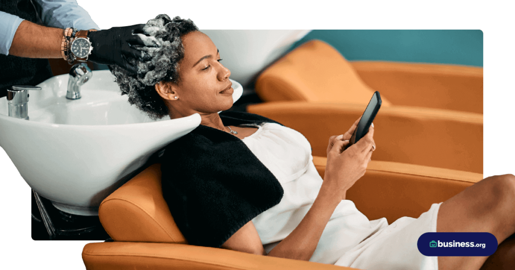 woman getting hair washed at salon using cell phone