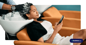 woman getting hair washed at salon using cell phone