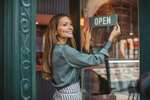 Small business owner placing open sign on door