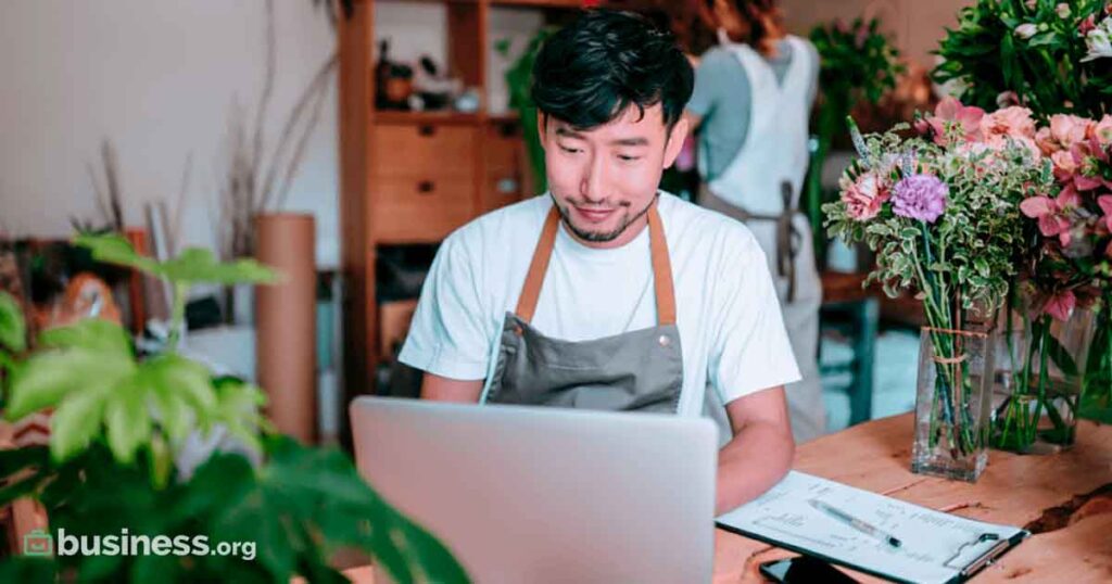 asian-male-using-laptop-wearing-work-apron